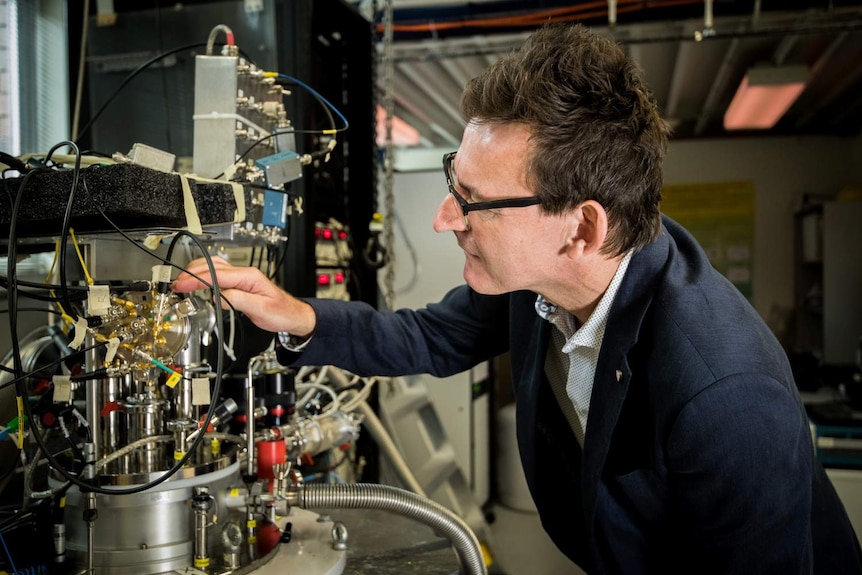 A scientist examines the dilution refrigerator in his quantum measurement lab. It is a complicated device with several wires