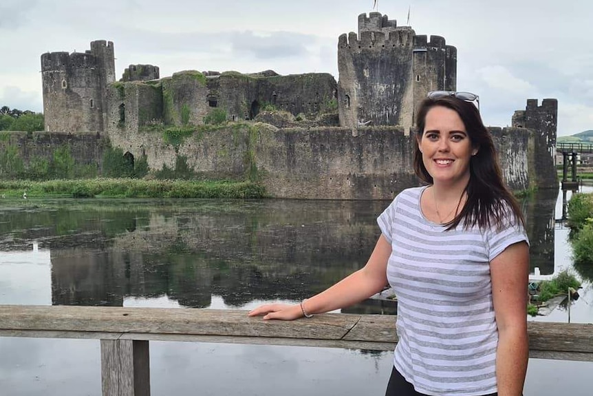 Louise Faint poses for a photo in front of an old castle.