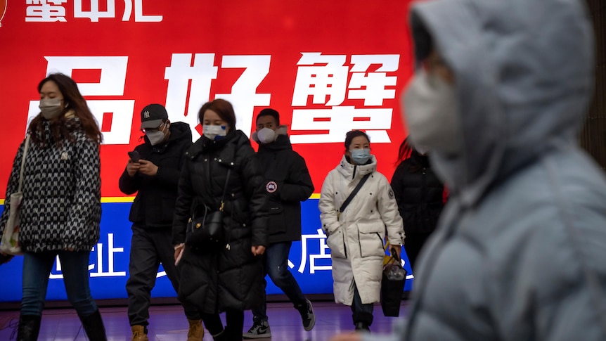 Commuters wearing face masks walk out of a subway station.