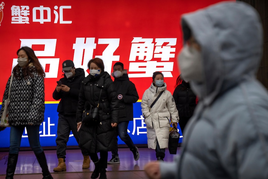 Commuters wearing face masks walk out of a subway station.