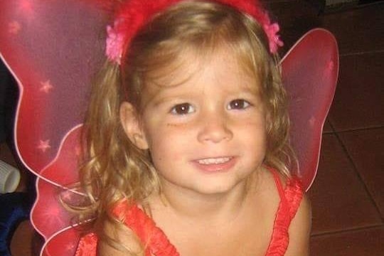 Kyanne smiling, brown eyes, blonde and brown hair wearing red angel wings and a headband.