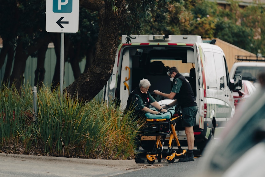 Paramedics load a stretcher into the back of an ambulance.