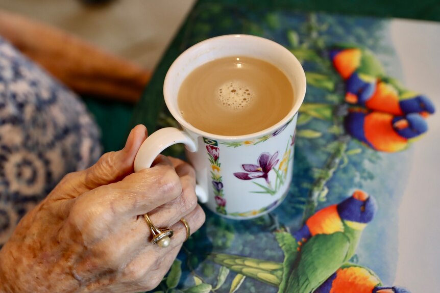 Close up of an old hand holding a cup of tea 