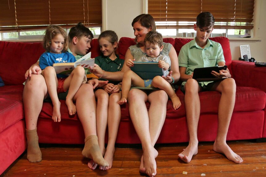 Merendi Leverett sits on a couch with her five children.
