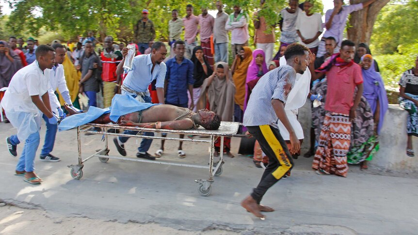 Emergency services rush a bloodied man on a stretcher.