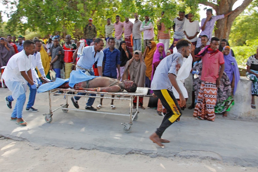 Emergency services rush a bloodied man on a stretcher.