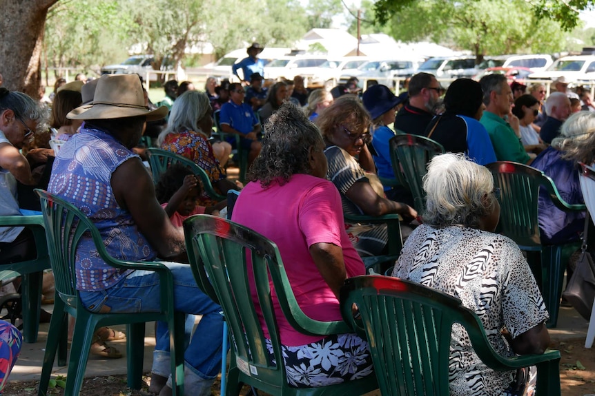 crowd sitting down listeningin park