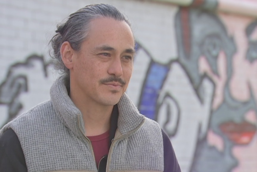 Melbourne artist Van T Rudd stands in front of his mural in Footscray.