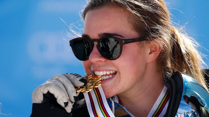 Britt Cox bites her gold during the medal ceremony at the 2017 world championships in Spain.