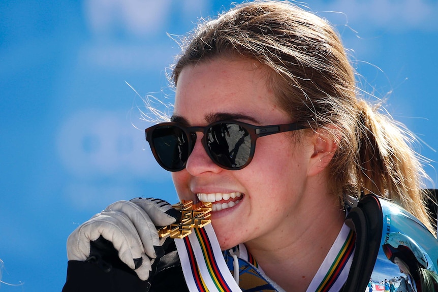 Britteny Cox bites her gold during the medal ceremony at the snowboarding and freestyle skiing world titles.