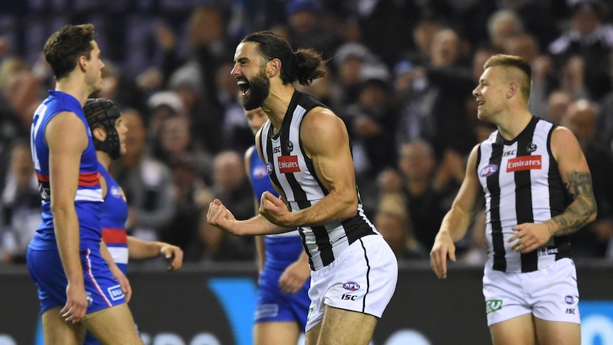 Colligwood AFL player Brodie Grundy screams and clenches his fist while running on the field against the Western Bulldogs.