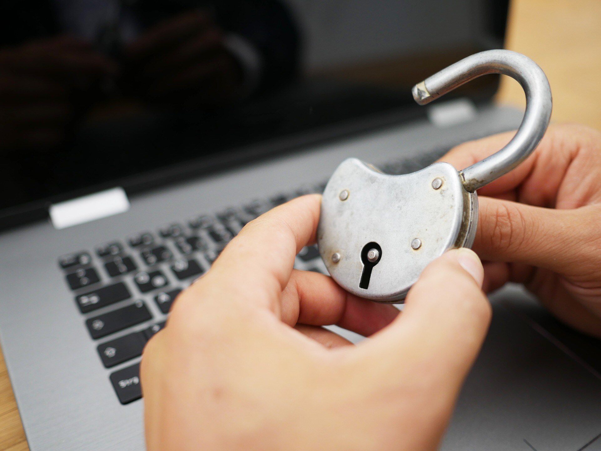 A person holds an open lock over a computer keyboard