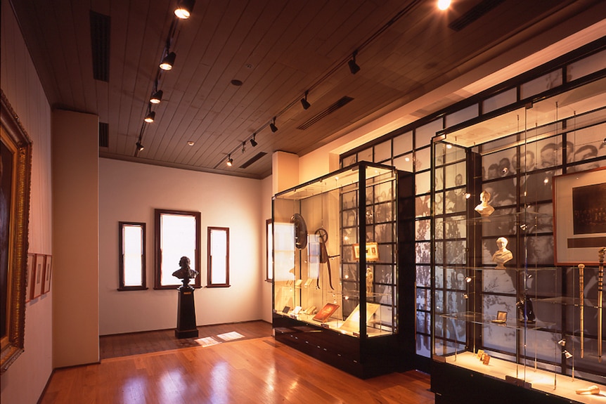 Inside a museum. Glass cases with busts, walking sticks.