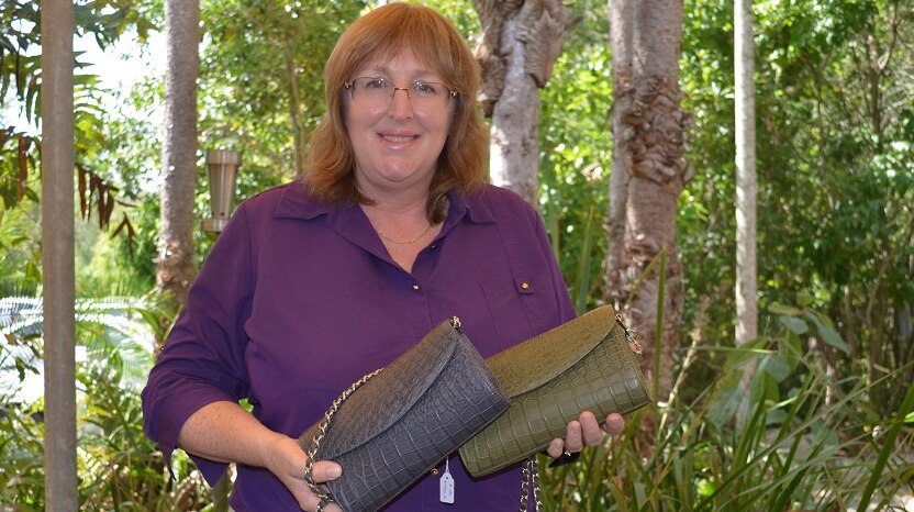 Angela Freeman holding two crocodile skin clutch purses