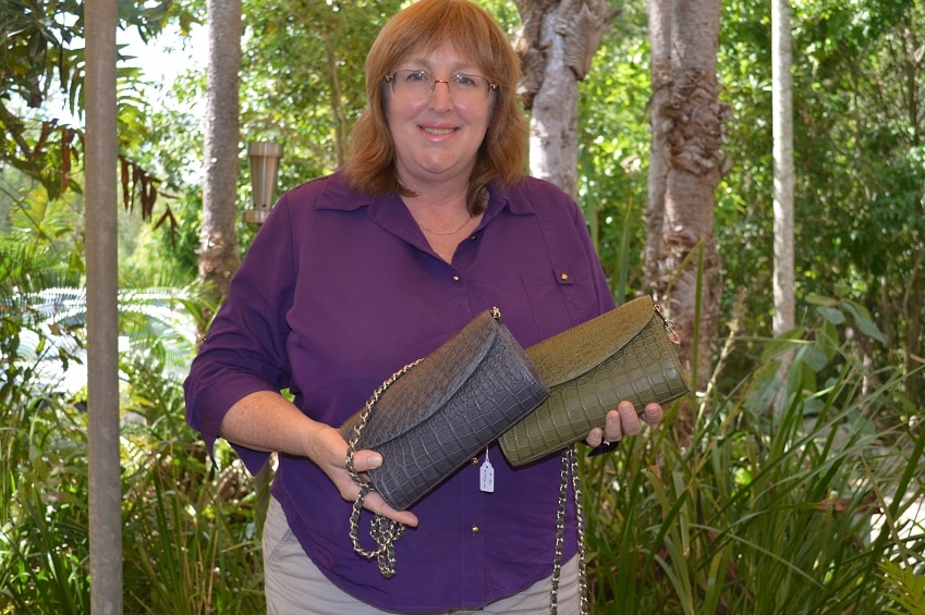 Angela Freeman hält zwei Clutch-Geldbörsen aus Krokodilleder in der Hand