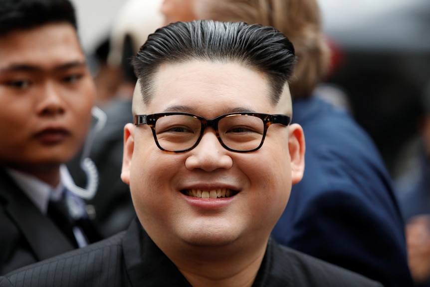 Close-up Howard X smiling.  He had short cropped black hair and black-rimmed glasses, resembling Kim Jong Un.