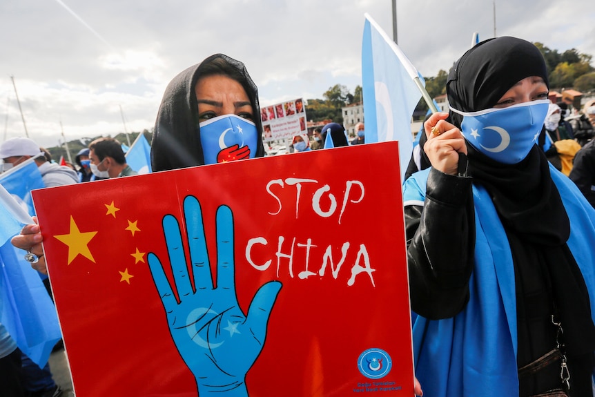 一名戴着头盔的女士手持一张写有“停止中国”字样的卡片。