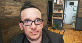 Close up of a man in black suit with glasses sitting in a cafe