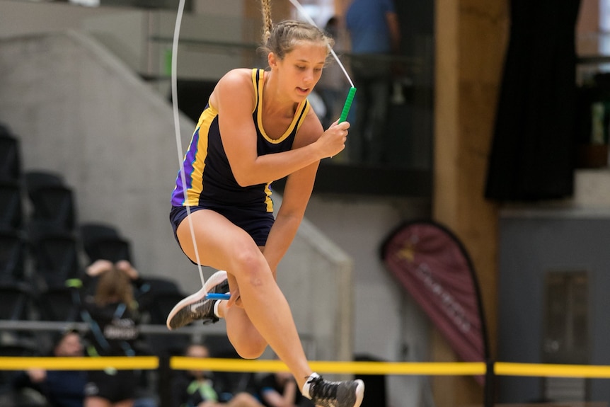 Lilly Barker jumps in the air and tucks her legs under as she clears a skipping rope.