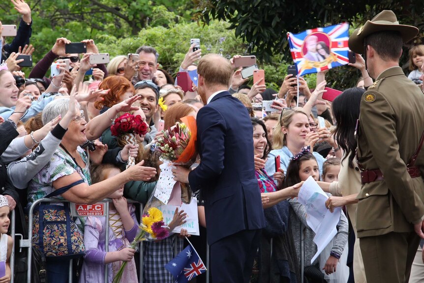 Fans stretch their hands out to try and shake hands with Prince Harry.