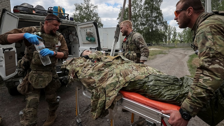 Military paramedics load a wounded Ukrainian service member into an ambulance.