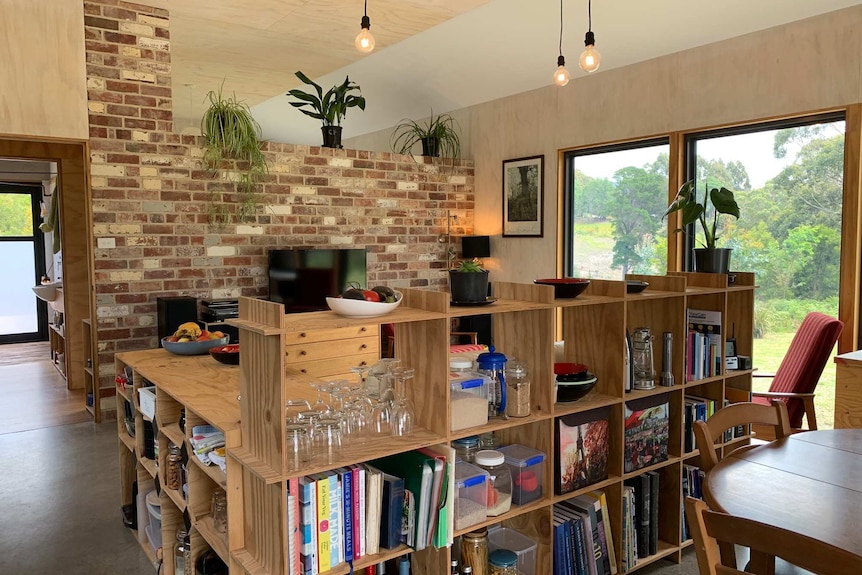 A living room, including hanging lights, a bookshelf, a table and television. It's very "Scandi", so bare wood, brick etc