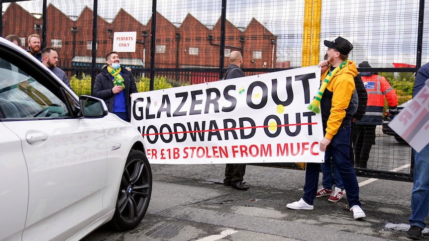 Fans blocking cars, holding signs saying 'Glazers out'