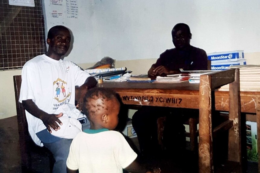 Two men at a desk and a toddler