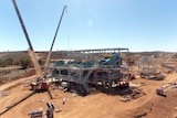 A wide shot of the Mt Marion lithium mine with a crane to the left of the mine structure.