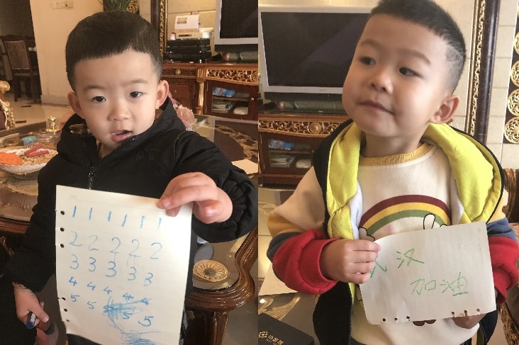 Composite image of two toddlers, holding sign saying Wuhan, add oil, meaning keep fighting.