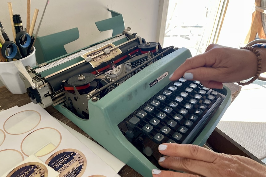 A green typewriter with a hand pushing keys.