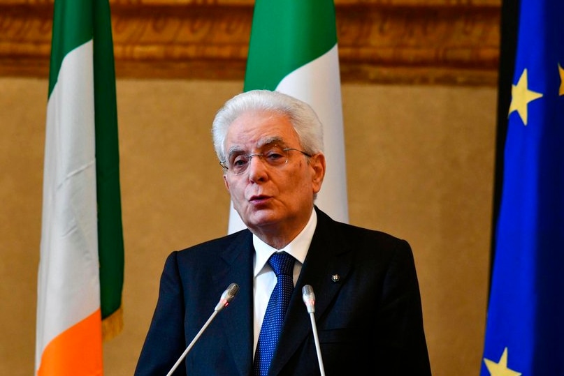 talian President Sergio Mattarella delivers a speech at a podium with flags behind him