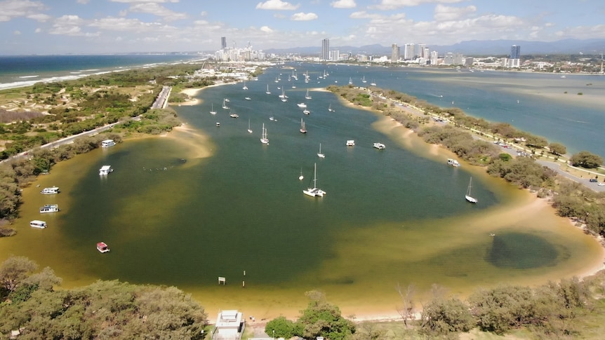 Drone photograph of a large bay where more than a  dozen boats are moored. 