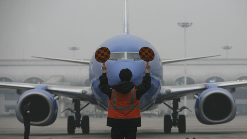 Arty shot of an airport worker waving a plane in at an airport