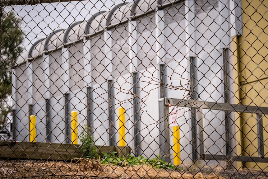 A hole in a wire fence outside a youth justice facility.