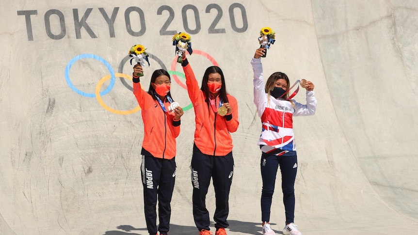 Female skateboarding holding up their medals at the medal ceremony 