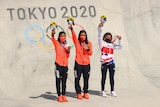 Female skateboarding holding up their medals at the medal ceremony 