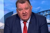 A close up of MP Craig Kelly on television with the Sydney Harbor bridge in the background