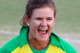 Jess Jonassen smiles and celebrates by clenching her hands wearing a yellow cricket kit