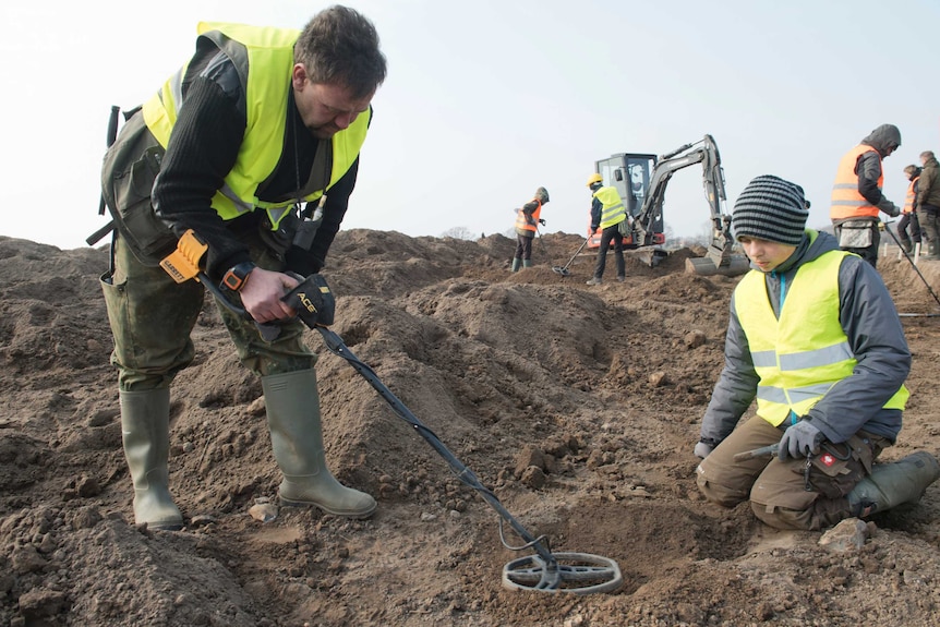 Archaeologist Rene Schoen is using a metal detector and 13-year-old Luca Malaschnitschenko is sitting next to him.