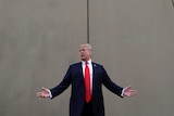 President Donald Trump speaks as he stands in front of a sand-coloured wall