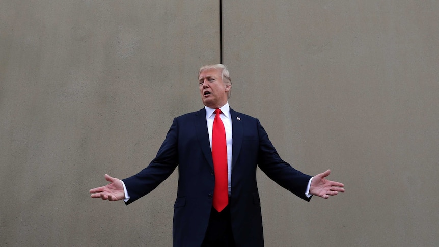 President Donald Trump speaks as he stands in front of a wall