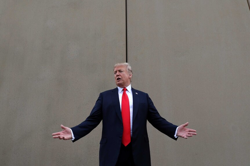 President Donald Trump speaks as he stands in front of a wall