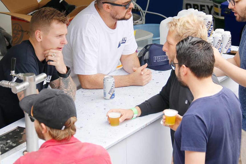 Two men talk to a bar tender.