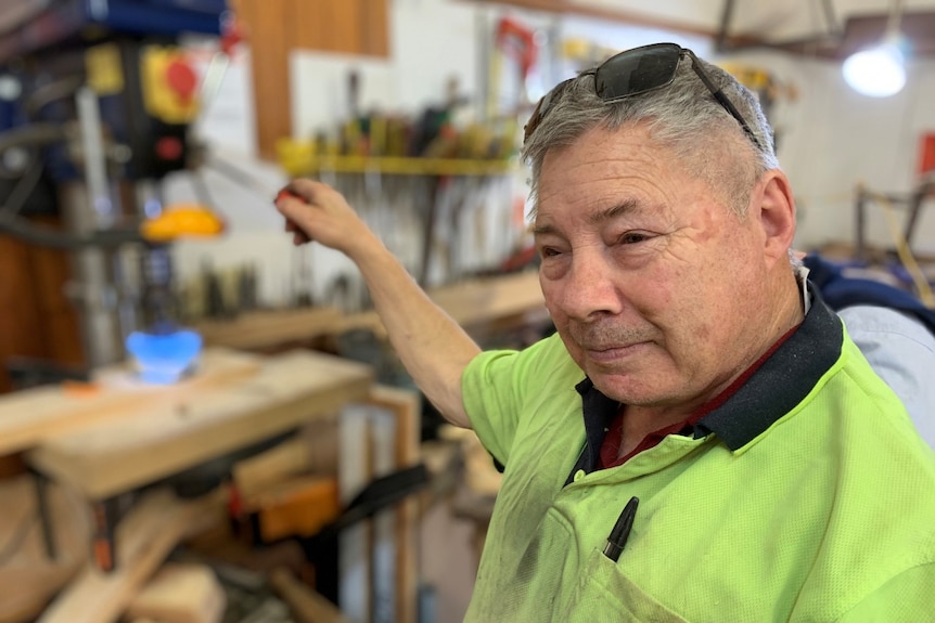 A man with greying hair holds a ruler