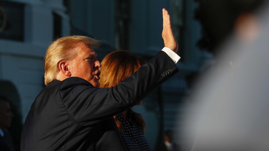 Donald Trump waves standing next to first lady Melania Trump at the South Lawn of the White House.