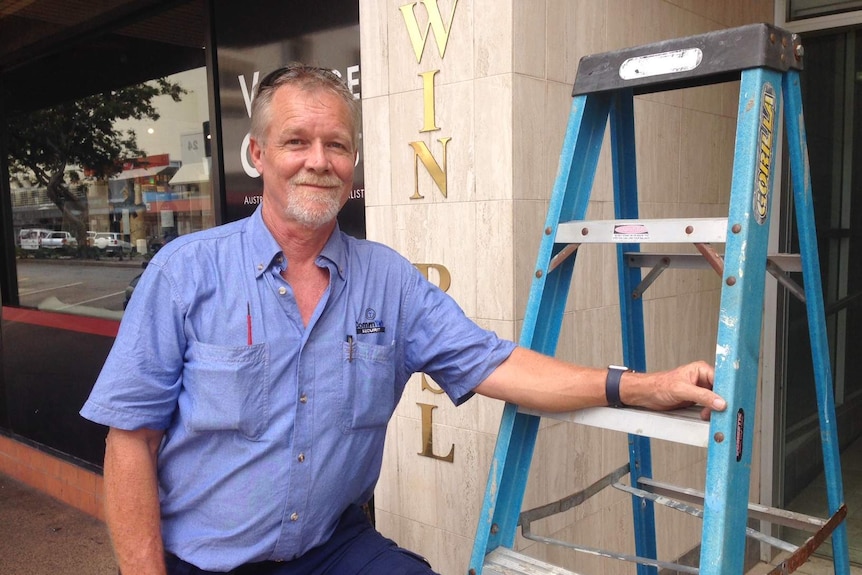 Security system installer Matthew Donogue with a ladder outside a Darwin business