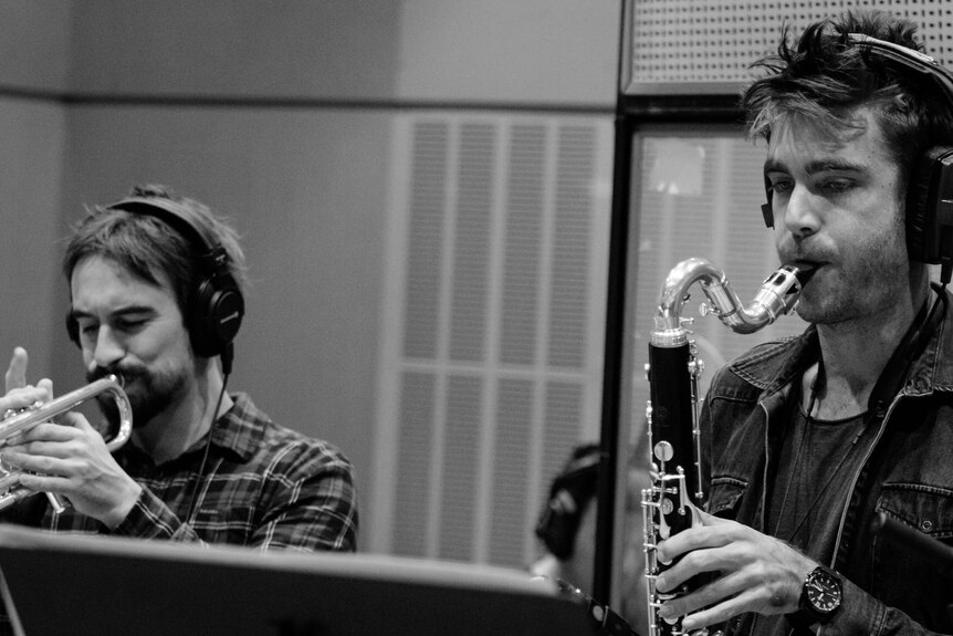 Black & white photo of Nick Garbett playing trumpet and Jeremy Rose playing saxophone on the ABC studio. Both wear headphones