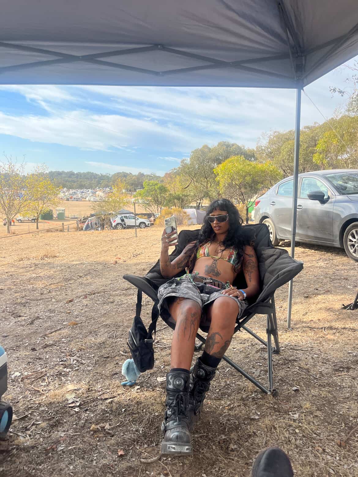 Uma jovem sentada em uma cadeira de acampamento em um festival de música 