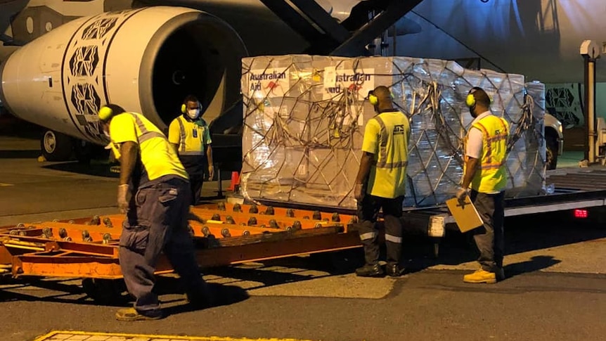 Airport workers unload cargo marked Australian Aid from a plane.